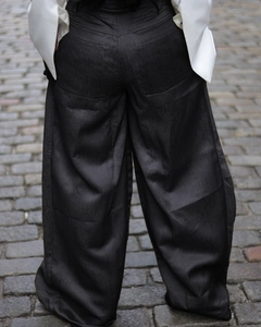 Close-up of high-waisted wide-leg trousers with vertical texture and rear pocket detail