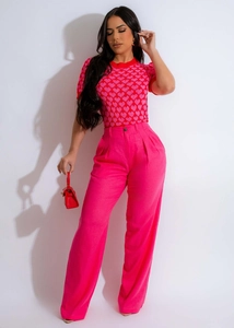 Close-up detail of heart pattern knit top and bright pink wide-leg trousers on model