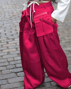 Detail of vibrant magenta cargo pants with tactical 3D pockets and white drawstring cord
