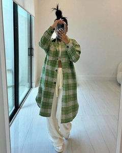 Detalle de chaqueta larga de cuadros verde y blanco con bolsillos y cuello de solapa