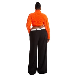 Dettaglio del maglione corto in mohair arancione abbinato a pantaloni neri a gamba larga