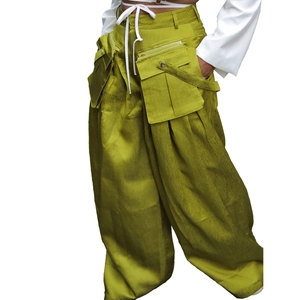 Detail of olive green wide-leg cargo pants with large pockets and metal zipper accents