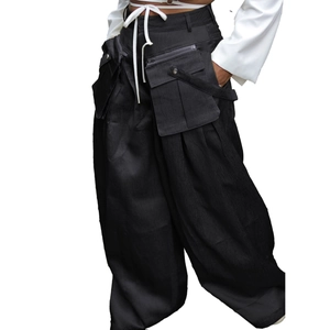 Detail of black wide-leg techwear pants with white drawstring and large cargo pockets