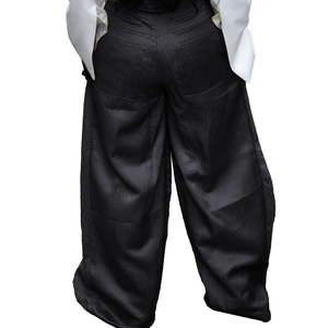 Detail of high-waisted black wide-leg trousers featuring vertical texture and rear patch pockets