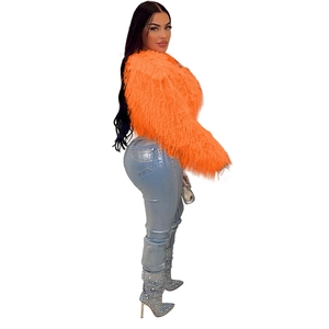 Detail einer leuchtend orangefarbenen Kunstpelzjacke mit funkelnden Strass-Stiefeln