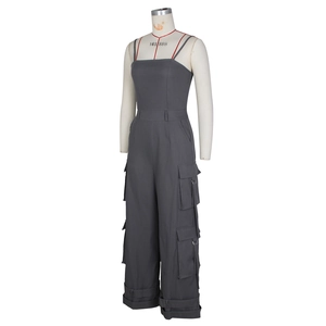 Detail of dark grey utility jumpsuit featuring cargo pockets and metal buckles