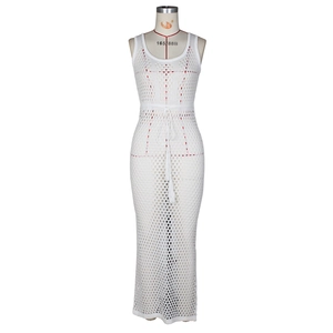 Détail de la robe de plage blanche au crochet montrant la texture ajourée et le cordon à glands