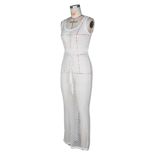 Détail d'une robe de plage en crochet blanc montrant la maille et le cordon à pompons