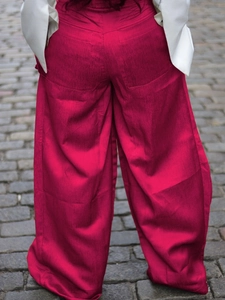 Vibrant rose red high-waisted wide-leg pants with textured fabric and back pockets
