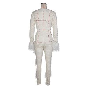 Detail of crochet hollow-out fabric and soft feather trim on cream white jumpsuit