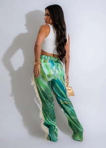 Detail view of colorful abstract print pants featuring white tassel fringe along the side