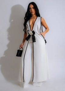 Detail of white sleeveless jumpsuit with black contrast trim and large floral bow