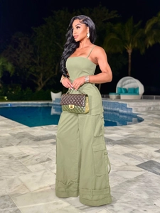 Olive green strapless cargo jumpsuit with wide legs and pockets shown in a poolside setting