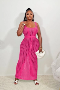 Détail de robe longue de plage rose vif au crochet avec motifs ajourés et pompons à la taille