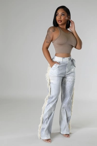 Detailed view of women's tie-dye trousers featuring long white fringe on the side seams