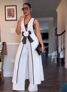 Detail of camellia flower and black bow accent on an elegant sleeveless vest and pants set