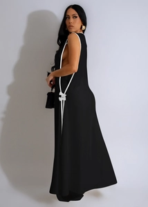 Detail of black maxi dress featuring white contrast piping and elegant bow accents