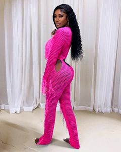 Detail of hot pink crochet jumpsuit featuring large mesh knit and long fringe tassels