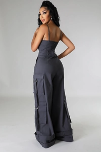 Detail of dark grey cargo jumpsuit with multiple utility pockets and buckle straps