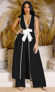 Detail of black V-neck jumpsuit featuring white contrast trim and 3D fabric flower detail