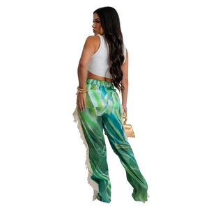 Detail of green gradient printed trousers featuring cream fringe trim and high waist