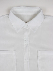 Detailed close-up of white sheer shirt with vertical texture and flap chest pockets
