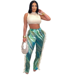 Detail view of teal print trousers with white side tassels and a sleeveless crop top