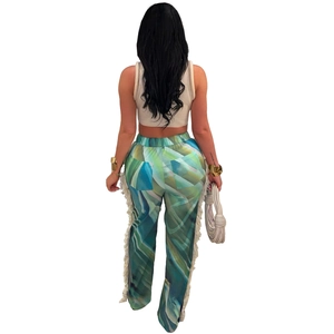 Detail view of abstract printed pants showing the flowy white side fringe and vivid colors