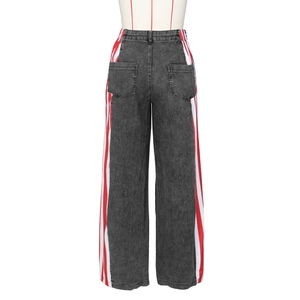 Dettaglio dei pantaloni a gamba larga in denim nero con strisce laterali rosse e bianche