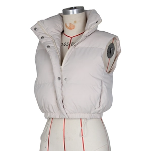 Detail view of beige quilted puffer vest with stand collar and adjustable drawstring hem