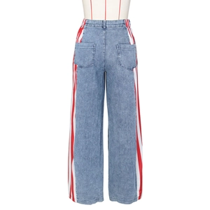 Dettaglio dei jeans a gamba larga a vita alta con strisce laterali rosse e bianche