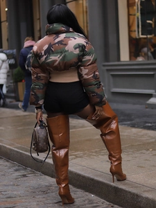 Women's trendy camouflage puffer jacket paired with stylish brown stiletto thigh high boots
