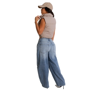 Side view of trendy khaki cropped puffer vest paired with wide-leg light blue denim jeans