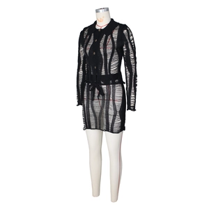 Détail de la robe courte en maille noire avec découpes ajourées et fermeture boutonnée