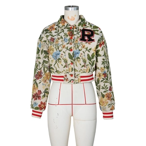 Detailed macro view of floral jacquard fabric texture and red button on short jacket