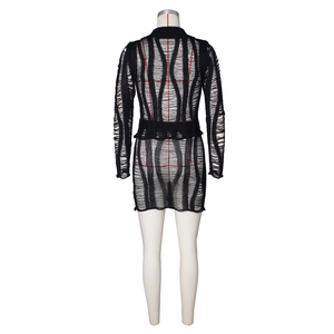 Détail d'une robe en maille noire avec découpes ajourées et effet déchiré sur le dos