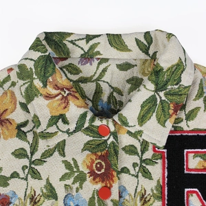 Close-up of vintage floral jacquard fabric with red buttons and letter embroidery
