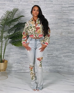 Detail view of vintage floral baseball jacket with ribbed cuffs and distressed denim pants