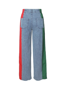 Detail of high waist denim trousers featuring red and green side panels and elastic waist