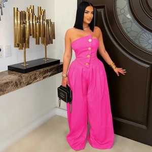 Detail of fuchsia strapless jumpsuit featuring asymmetrical neckline and gold buttons