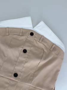 Dettaglio dell'abito trench senza maniche kaki con revers bianchi a contrasto e bottoni neri