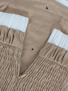 Dettaglio della vita a pieghe kaki con bordo bianco e chiusura a zip invisibile