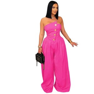 Detailed view of hot pink strapless top with gold buttons and high-waist wide-leg trousers