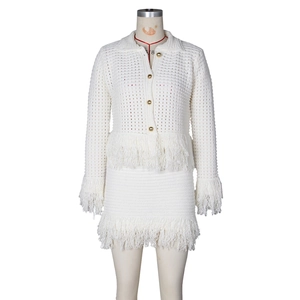 Detailed view of cream knit set featuring golden buttons and long fringe tassel trims