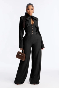 Close-up of black pinstripe jumpsuit featuring elegant bow neck and brown button details
