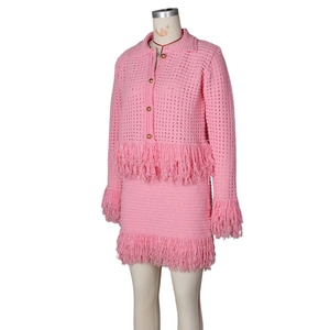 Detail of pink knit set featuring golden buttons and elegant fringe trim on the hem