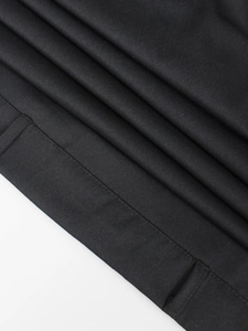 Dettaglio ravvicinato del tessuto twill nero con cuciture piatte su un abito trench senza maniche