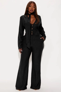 Detail of elegant black pinstripe jumpsuit featuring a deep V-neck and amber button accents