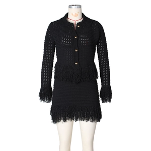 Detail of black crochet knit two-piece set with gold buttons and long fringe trim