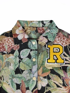 Detail of vintage floral jacquard fabric with chenille R patch and gold metal buttons